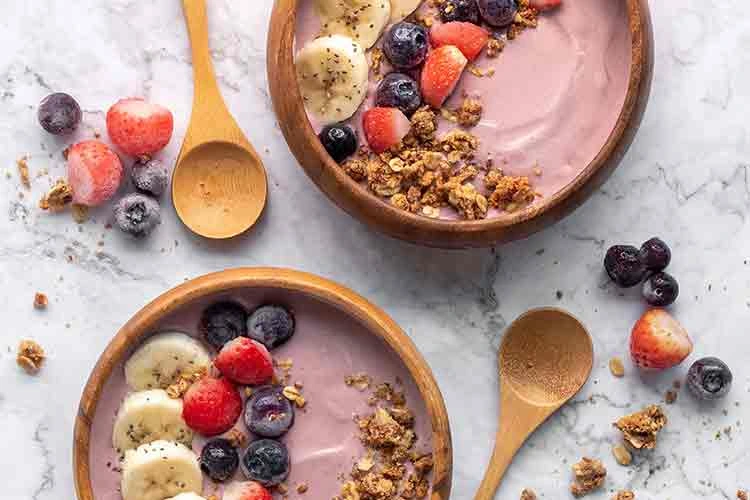 Two acai bowls with barries, banana, and granola