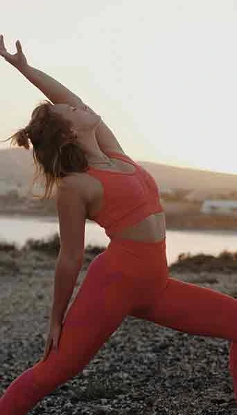 Women outside in a red activewear set in a lunge pose