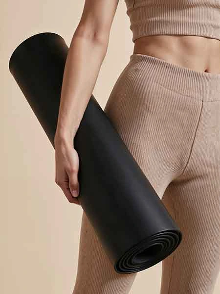 women holding a rolled up black yoga mat