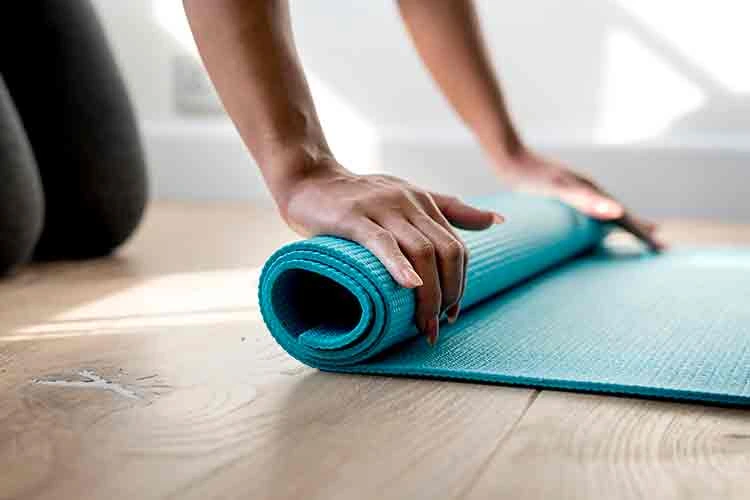 Blue yoga mat being rolled up by a person