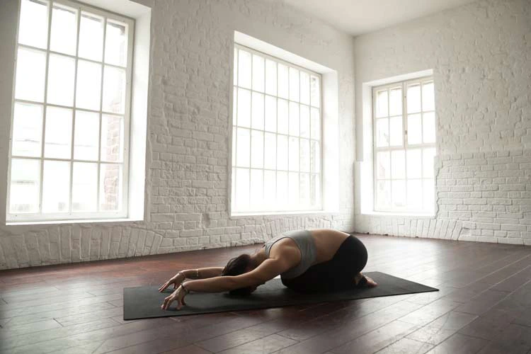 women doing a yoga pose on mat in a large room